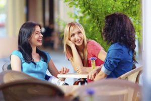 Three women sitting around a table laughing