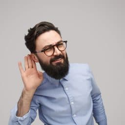 man putting hand up to ear in a listening fashion