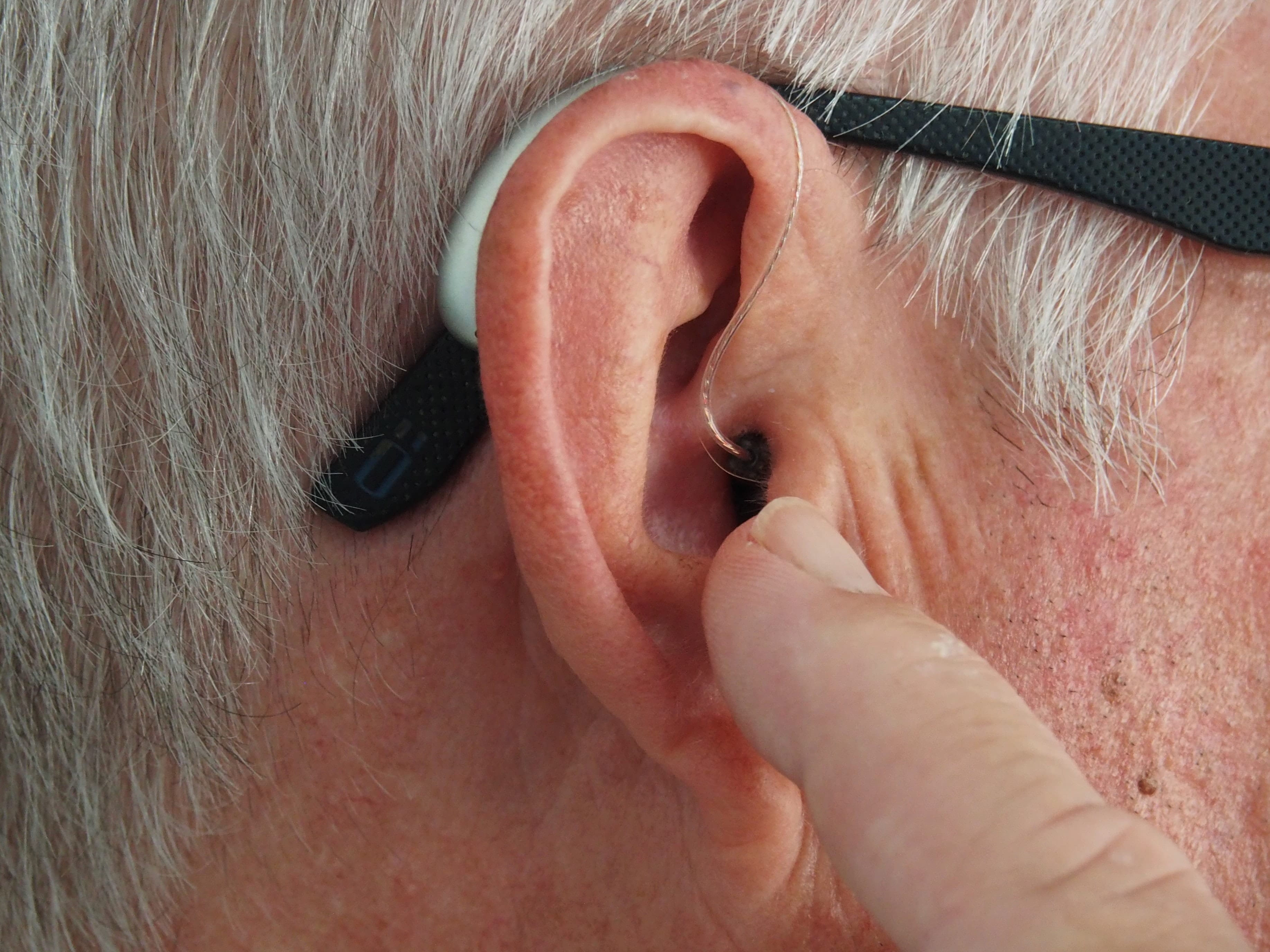 Older man touching his hearing aid while it's in his ear