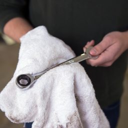 Mechanic wiping off wrench with towel.