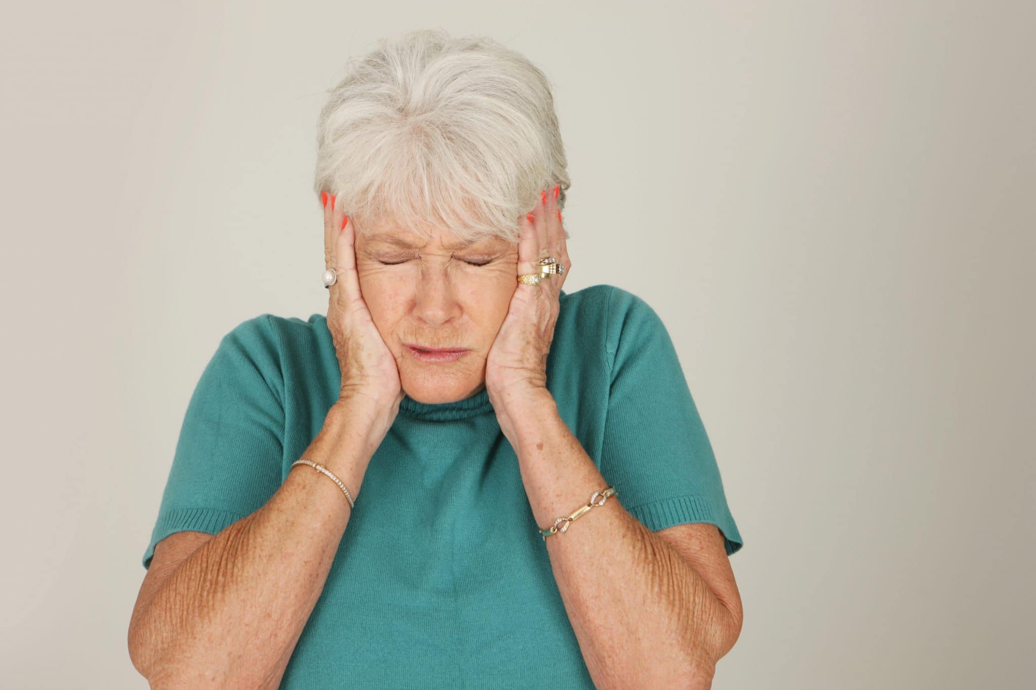 Older woman covering her ears.