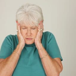 Older woman covering her ears.
