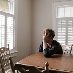 Depressed man sitting at his dining room table.