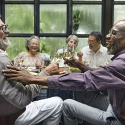 Group of older friends conversing at a dinner party.