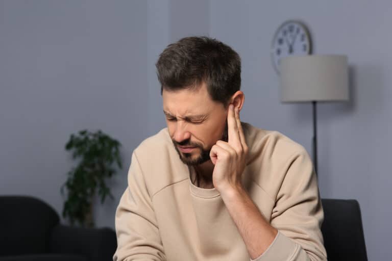 Man with tinnitus holds finger to ear