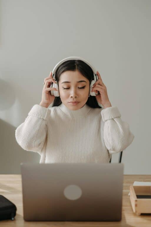 A woman with hearing aids puts over-ear headphones on 