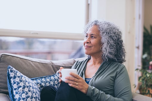 Contemplative woman in her home, relaxing on the couch with a cup of tea