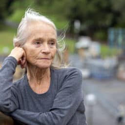 Portrait of senior woman outdoor with hand on chin looking away, background with copy space, full frame horizontal composition